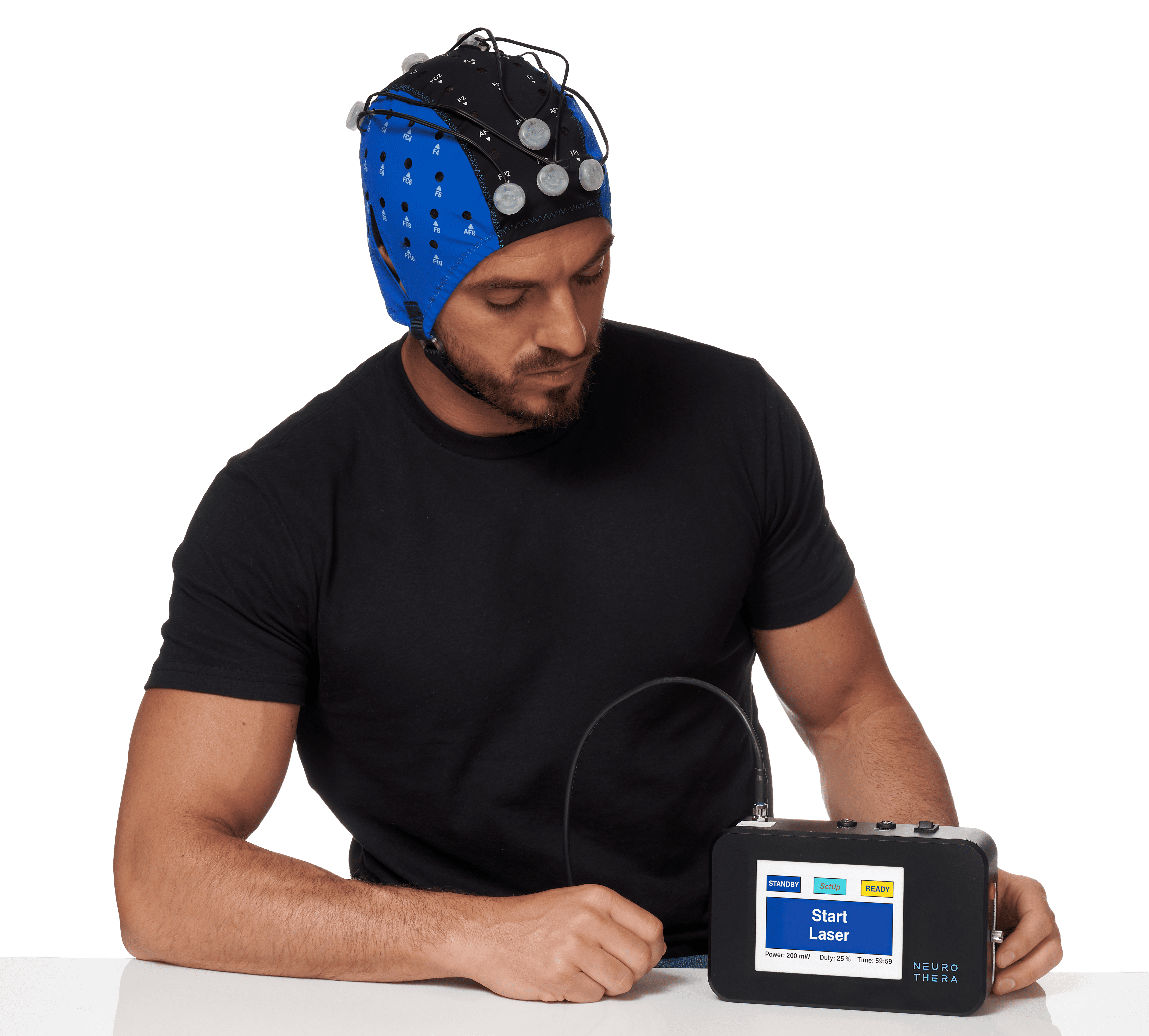 Model wearing an EEG headcap with tPBM diodes loaded, sitting behind a table with the Neurothera tPBM device